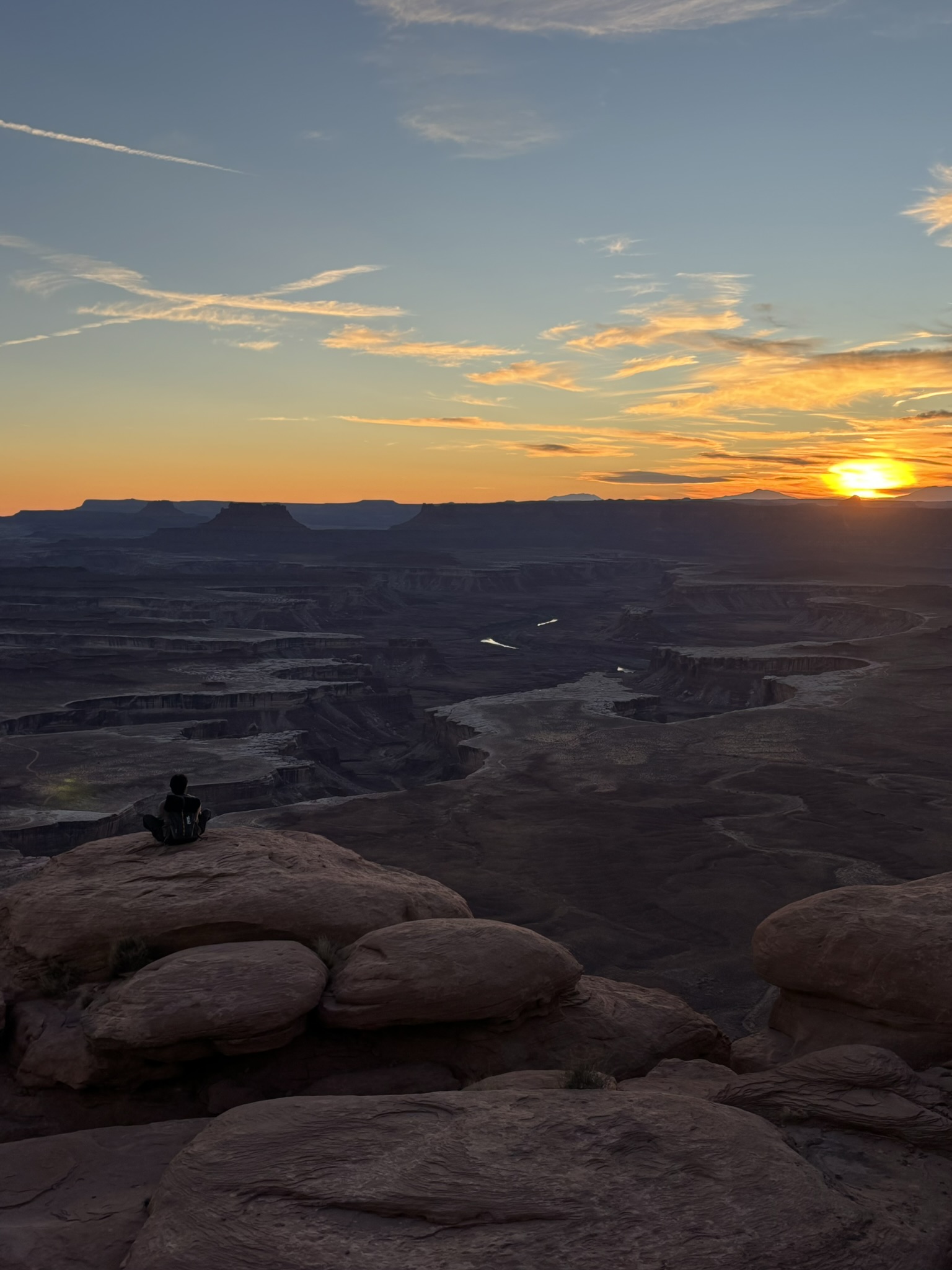 A lone hiker overlooking a canyon landscape at sunset